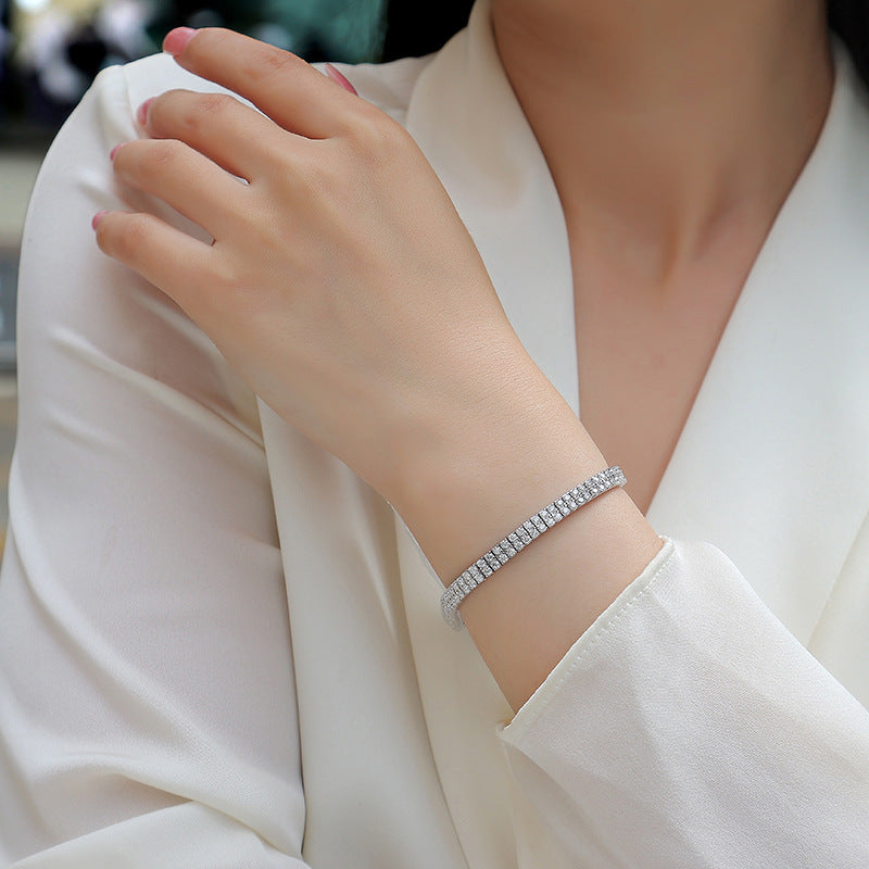 Bracelet stacked with other pieces. Alt: “Stackable Luxury: Double-Row Moissanite Bracelet.”