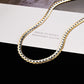 Gold and silver chain necklace on a black and white striped surface