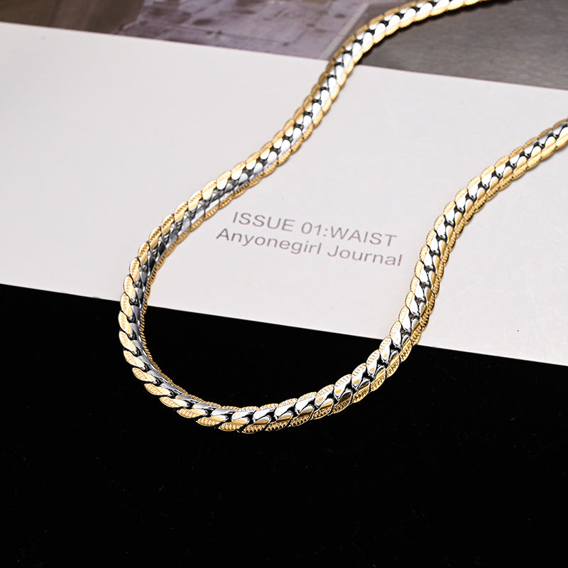 Gold and silver chain necklace on a black and white striped surface