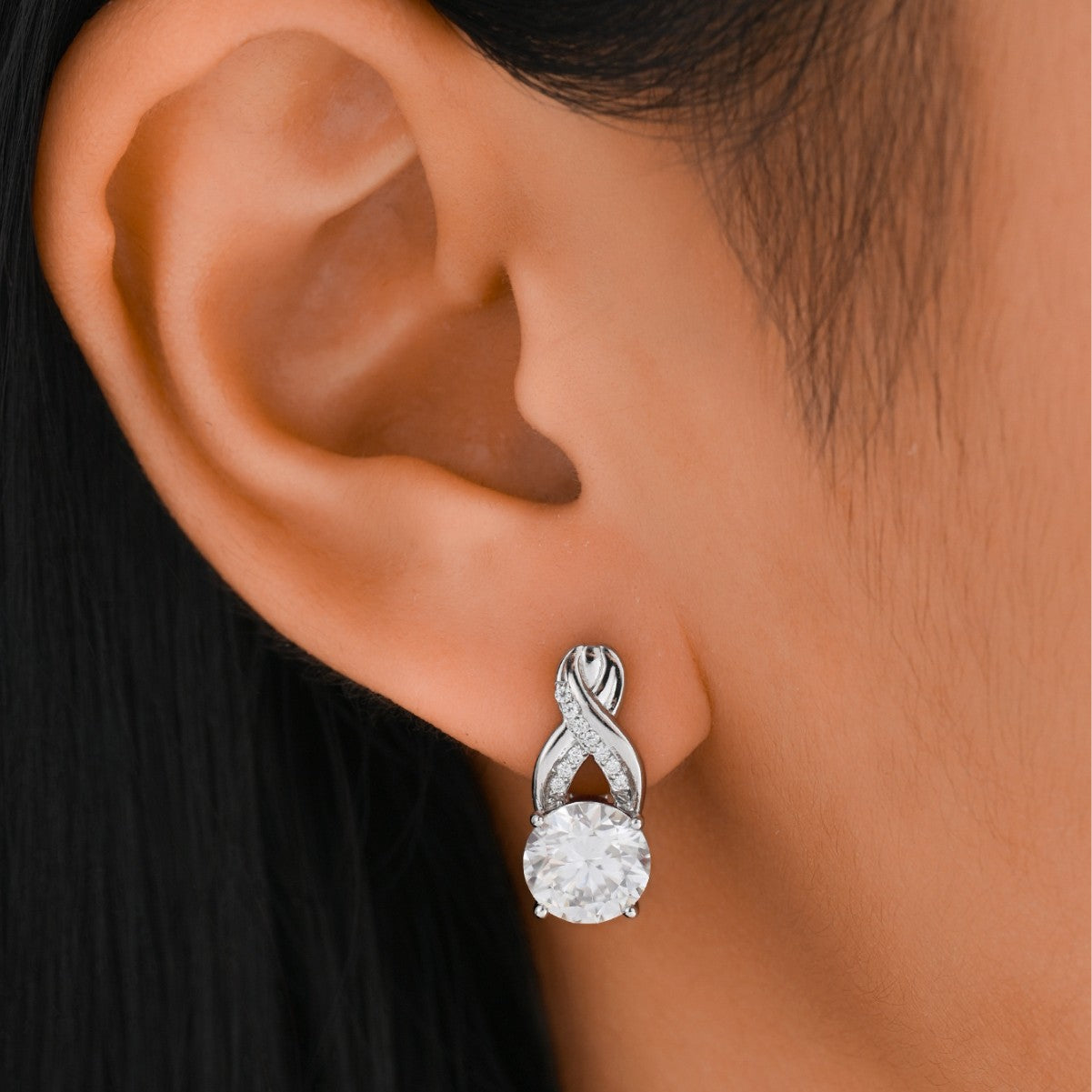 Earrings worn as symbolic statement. Alt: “Endless Sparkle: Infinity Moissanite Earrings.”
