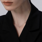 Person wearing a delicate necklace with a plain background