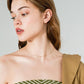 Woman wearing a strapless green and white patterned top with a beige cardigan on a light gray background