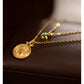 Gold necklace with a coin pendant on a dark surface