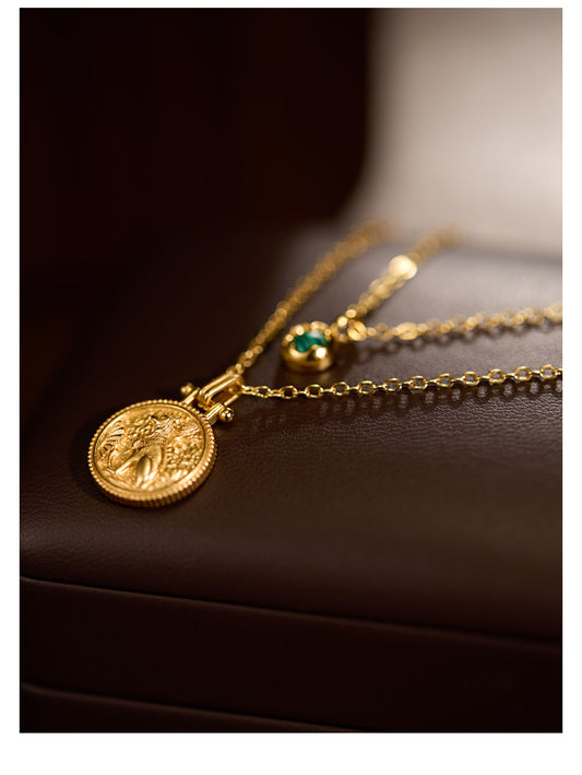 Gold necklace with a coin pendant on a dark surface