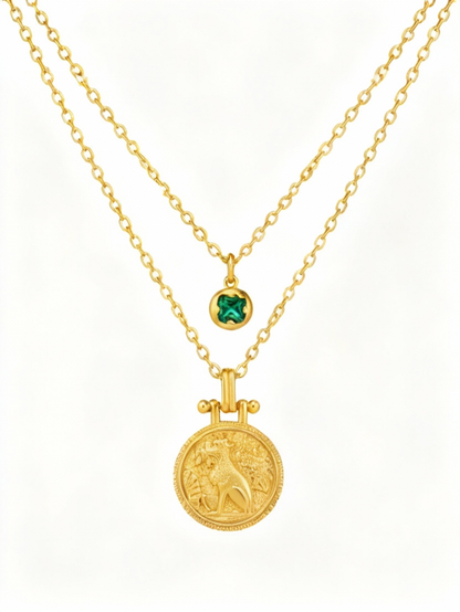 Two gold necklaces with a lion pendant and green gemstone on a white background