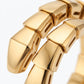 A close-up of a polished yellow gold snake-bone style bracelet, showing the textured, segmented scales and reflective metallic surface against a clean white background.