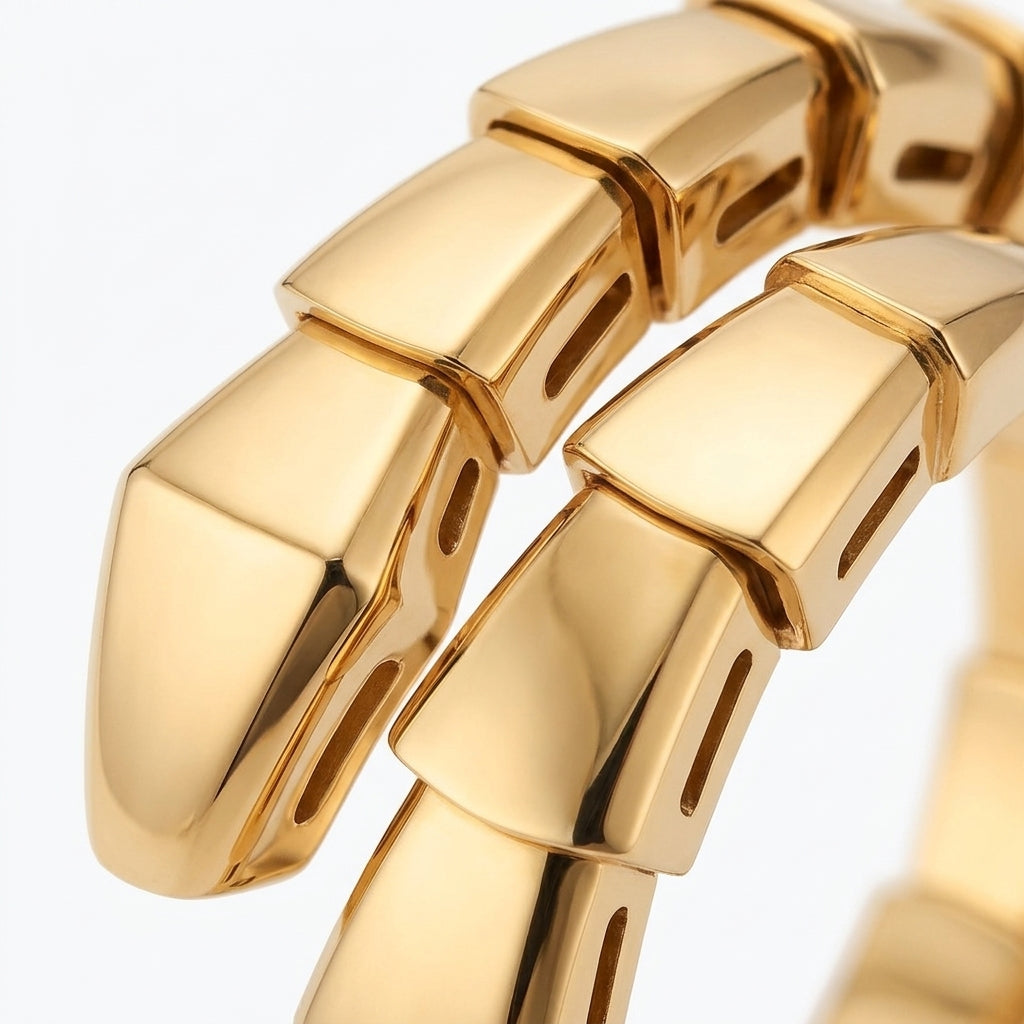 A close-up of a polished yellow gold snake-bone style bracelet, showing the textured, segmented scales and reflective metallic surface against a clean white background.