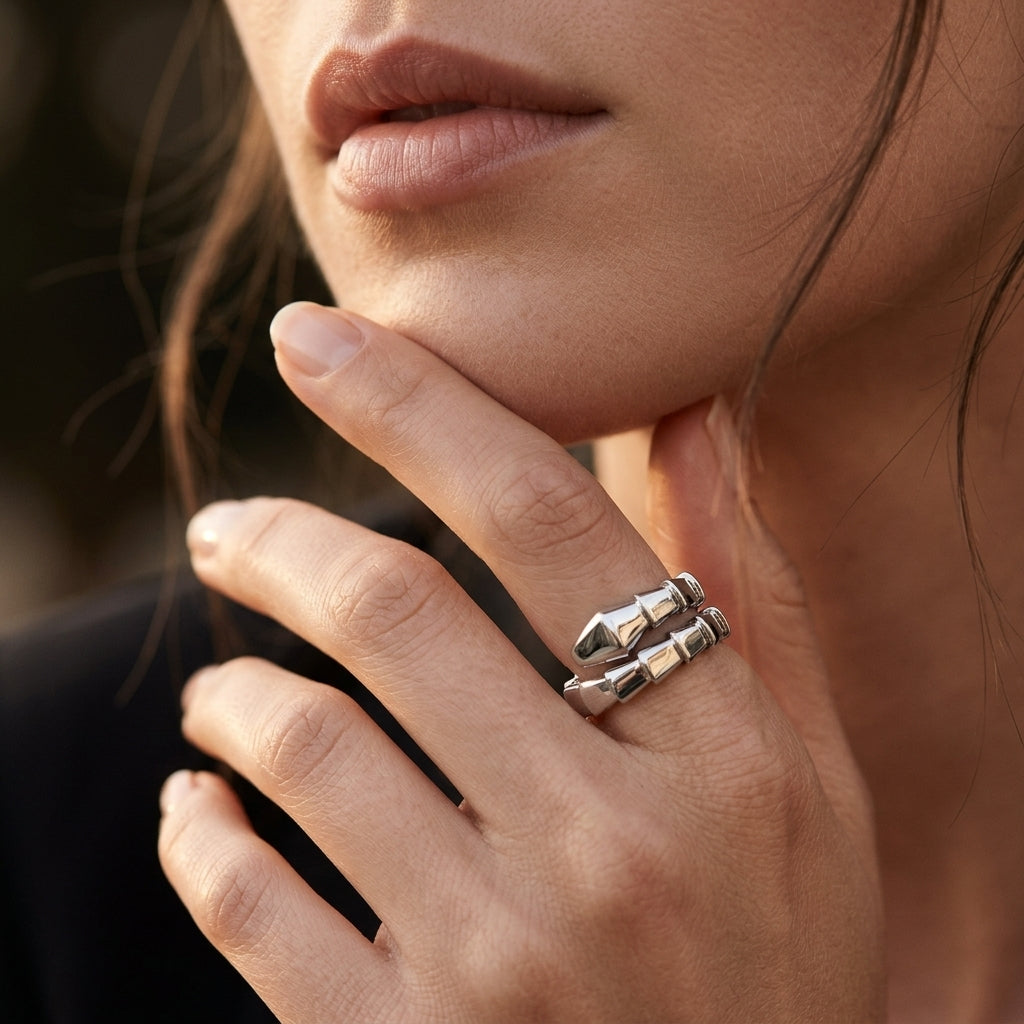 A close-up lifestyle shot of a model wearing a silver ring with three stacked, geometric, beaded finger-like segments on her ring finger.