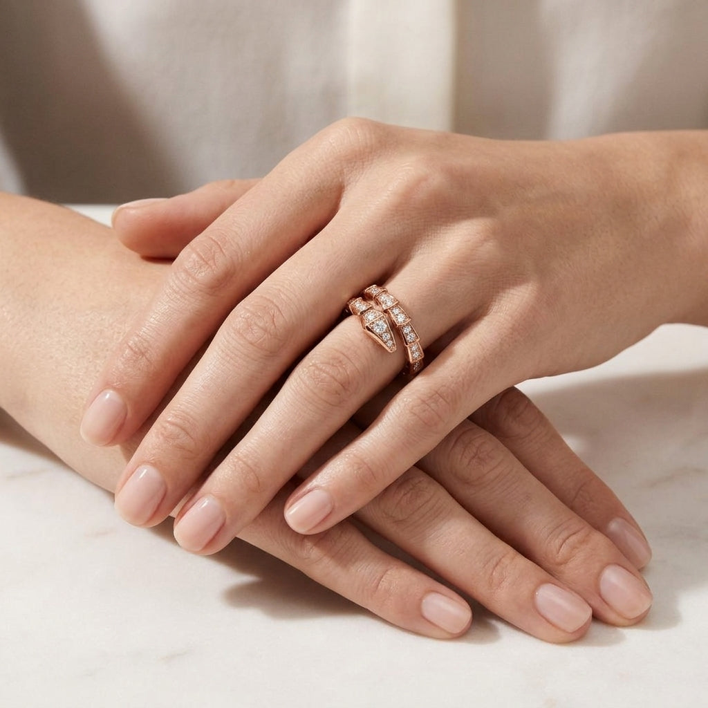 A close-up of a person's hands resting on a light marble surface, wearing two slim rose gold rings with pavé-set clear stones.