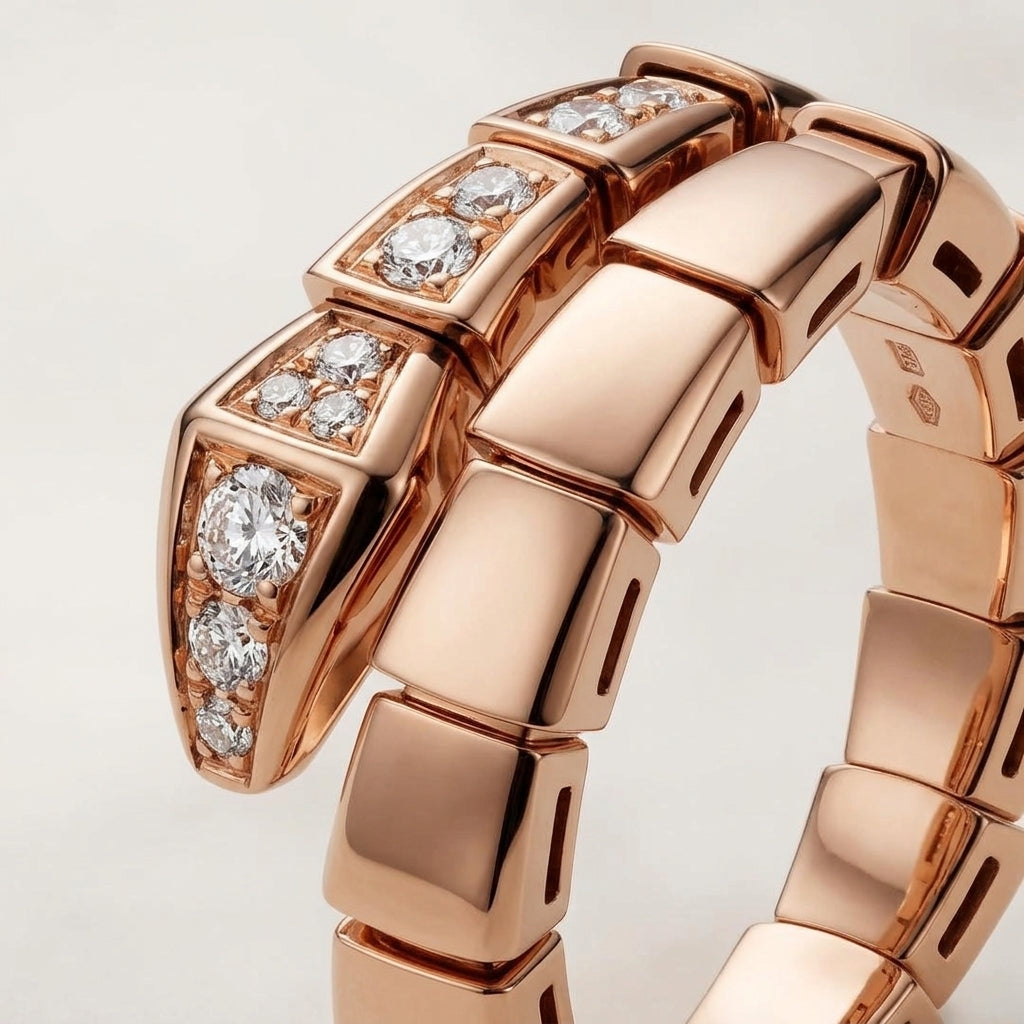 A close-up of a rose gold bracelet featuring a distinctive snake-head link design embellished with clear pavé and round diamonds, set against a clean light gray background.