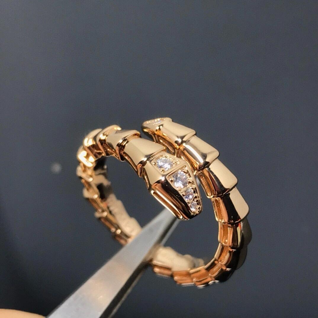 Gold ring with diamond accents held by tweezers against a dark background