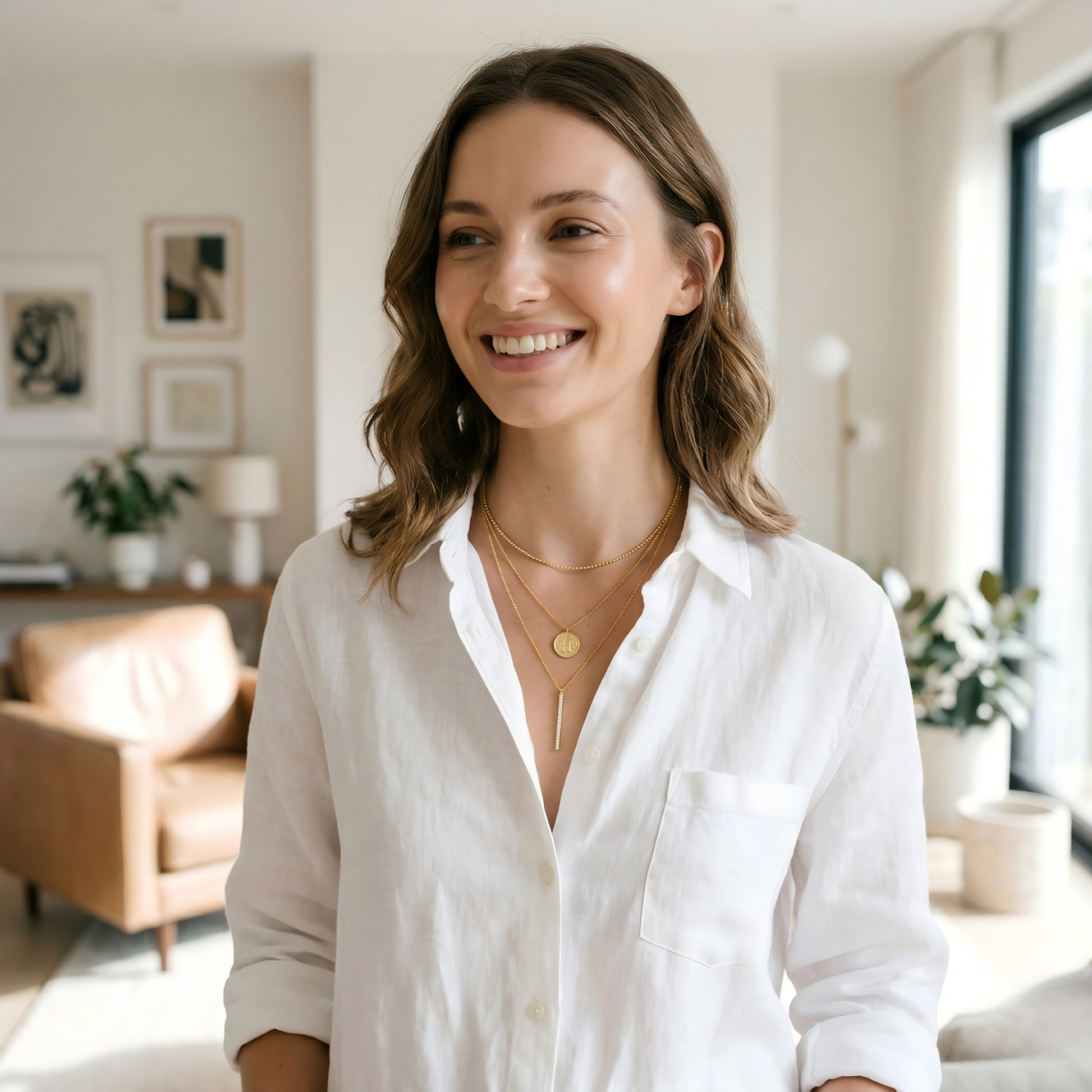 Natural lifestyle shot of a young woman wearing the necklace in a bright modern living room, soft side natural light, minimal white outfit, shallow depth of field, highlighting realistic wear and effortless luxury, magazine-style, 4K.