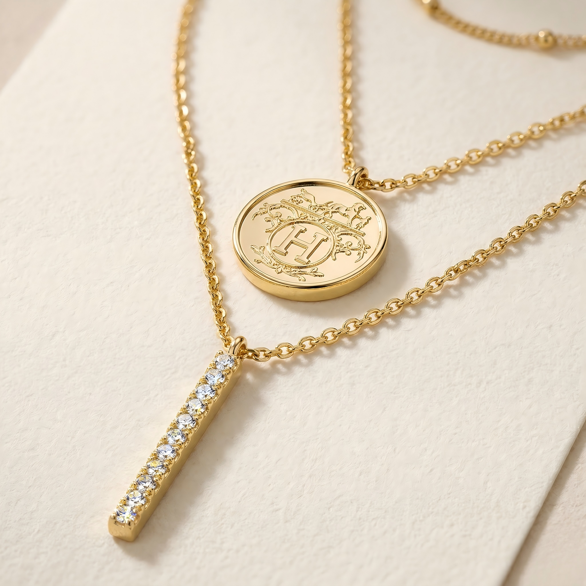 Extreme macro close-up of the necklace pendant, mirror-polished metal, sparkling stone facets under focused light, clean cream textured background, ultra-detailed luxury jewelry photography.