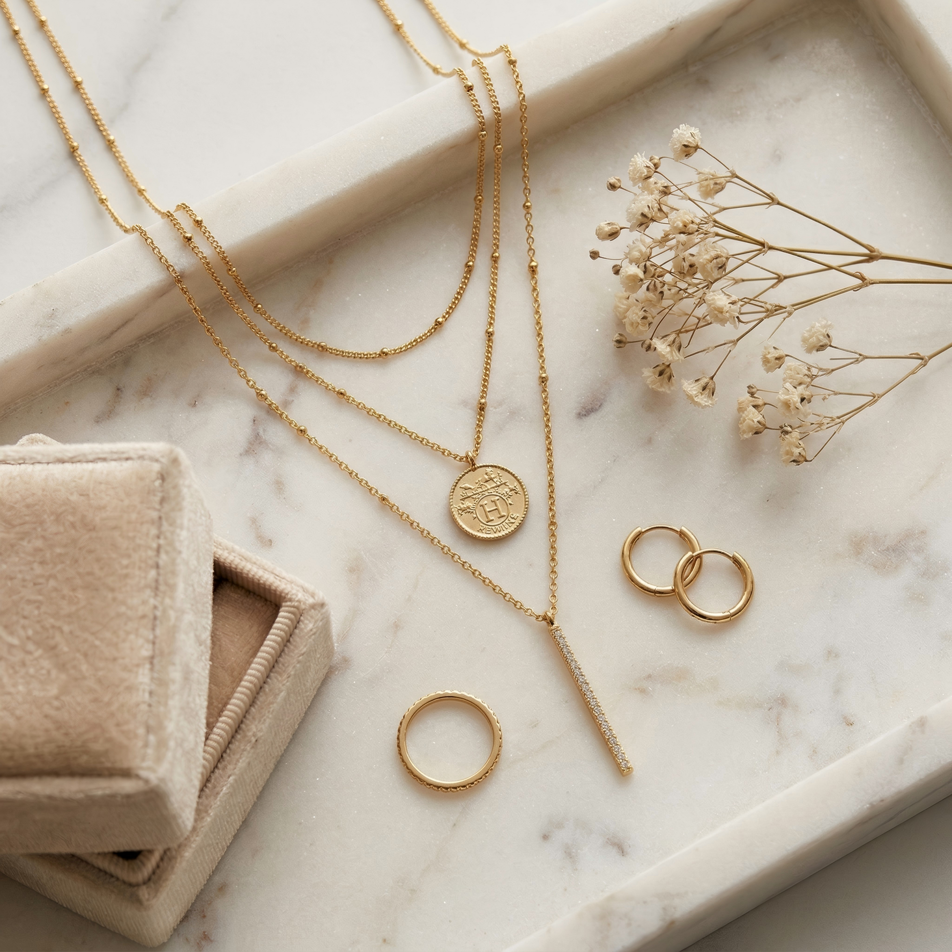 Top-down flat lay of the necklace on a white marble tray, styled with earrings, ring, dried flowers and a velvet jewelry box, soft warm tones, balanced composition, elegant e-commerce aesthetic.