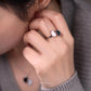 Close-up of a hand wearing a ring with a unique design, touching the ear.