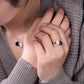 Person wearing a set of earrings and a ring with a neutral background