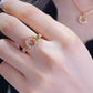 Close-up of a hand wearing a gold ring with gemstones on a blurred background