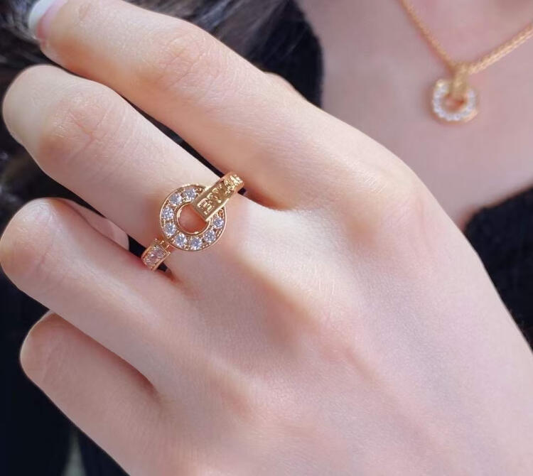 Close-up of a hand wearing a gold ring with gemstones on a blurred background