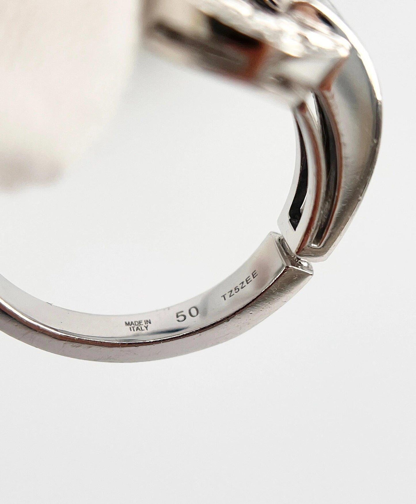 Close-up of a silver ring with 'Made in Italy' stamp on a light gray background