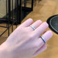 Hand wearing two silver rings with a blurred indoor background
