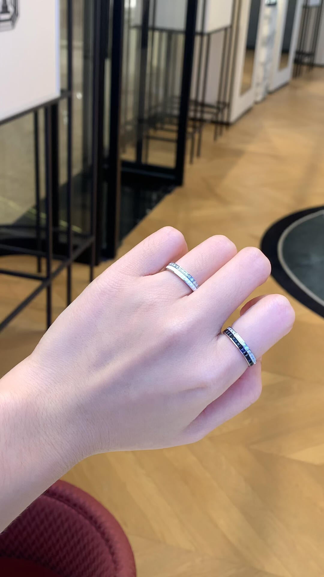 Hand wearing two silver rings with a blurred indoor background