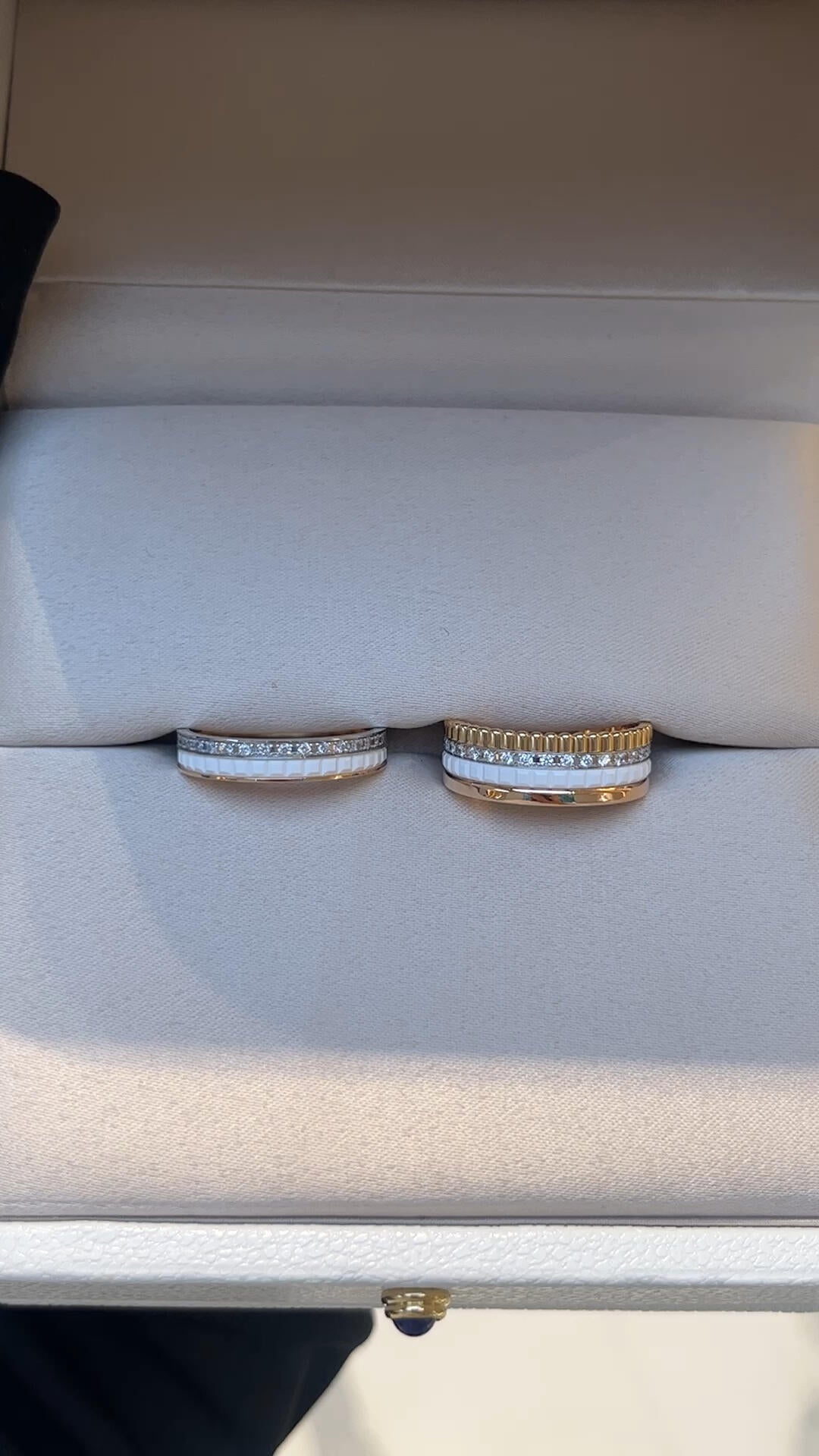 Two gold rings with diamond accents on a white jewelry box.