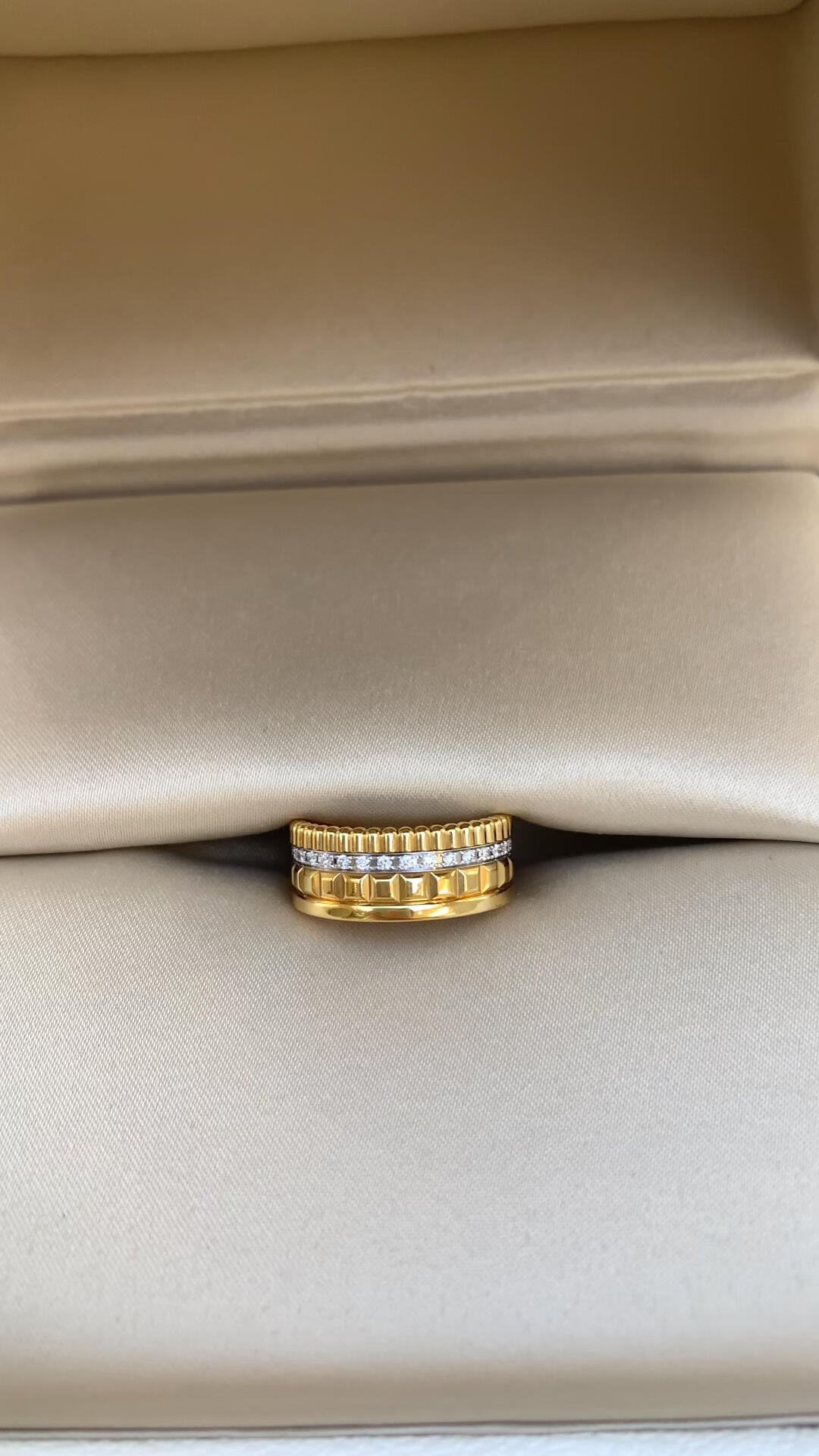 Gold ring with embedded diamonds on a beige fabric background