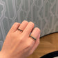 Hand wearing two rings with a patterned wall in the background