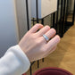 Hand wearing a silver ring with a blurred indoor background