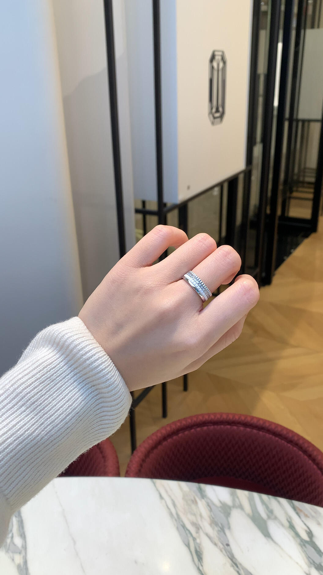 Hand wearing a silver ring with a blurred indoor background