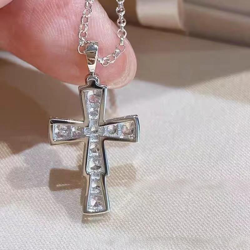 Bvlgari 18K White Gold Serpenti Cross Diamond Necklace Necklace Women Silver cross pendant with clear stones on a chain, held by a hand against a light fabric background.