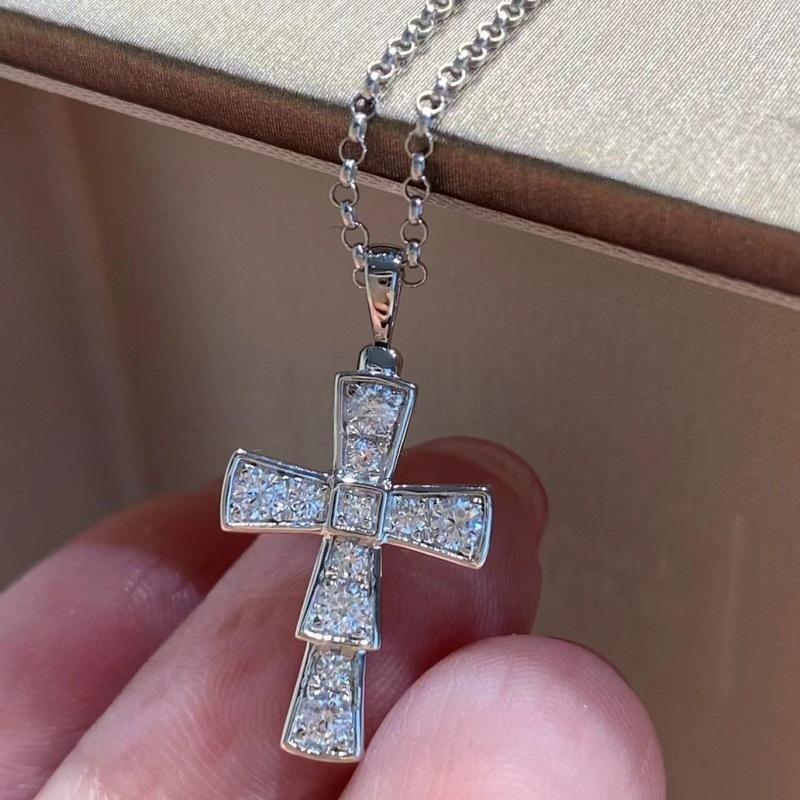 Bvlgari 18K White Gold Serpenti Cross Diamond Necklace Necklace Women Silver cross pendant with clear stones held by a hand against a neutral background