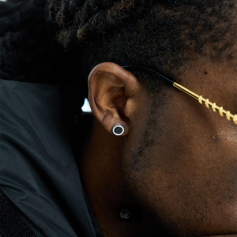 Close-up of an ear with a gold earring and black background