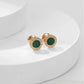 Gold earrings with green stones on a white background