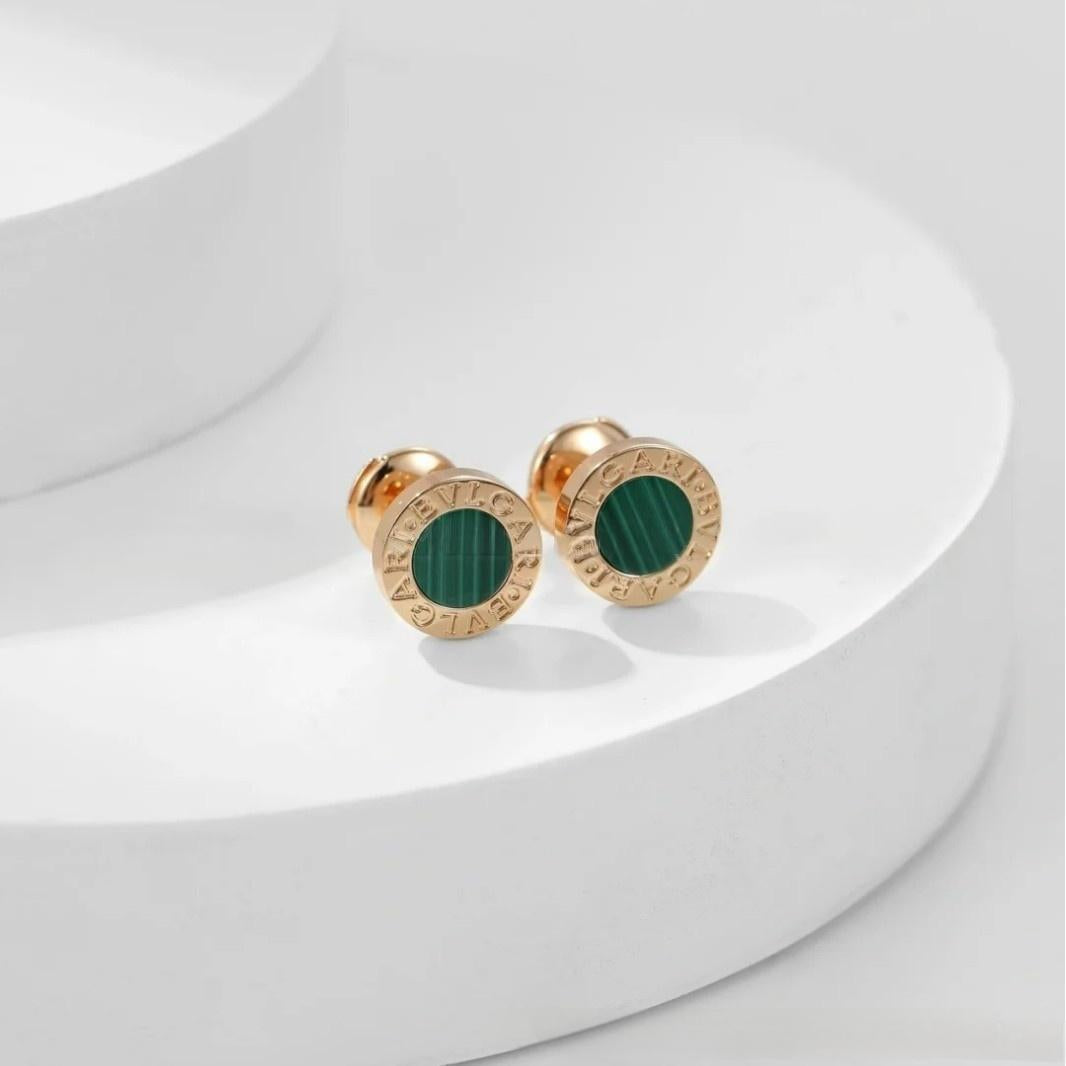 Gold earrings with green stones on a white background