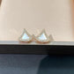 Bvlgari  Divas’ Dream Earringsand white triangle-shaped earrings on a beige surface.