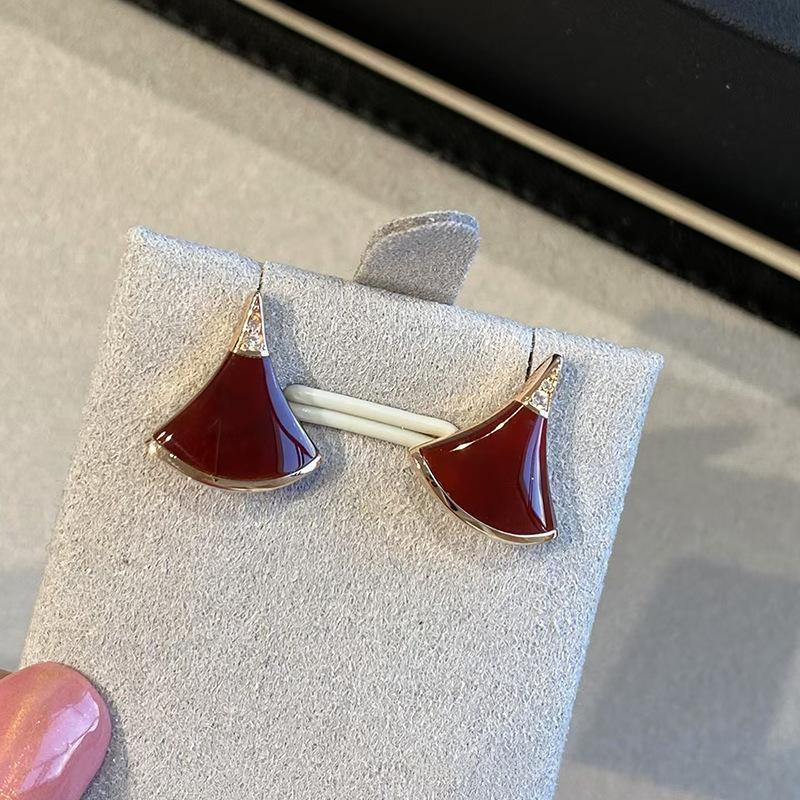 Bvlgari  Divas’ Dream Earringswith red and gold design on a gray stand.