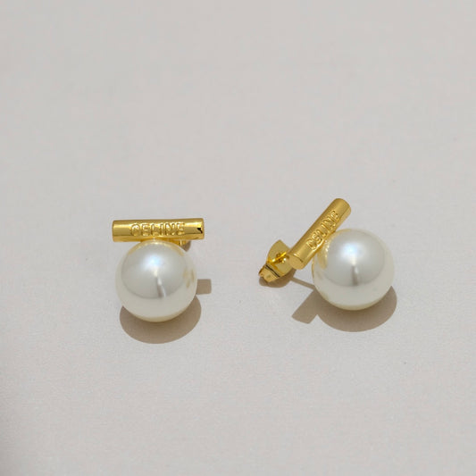 A pair of gold and pearl stud earrings on a light beige background, with one earring showing the front and the other showing the side profile.