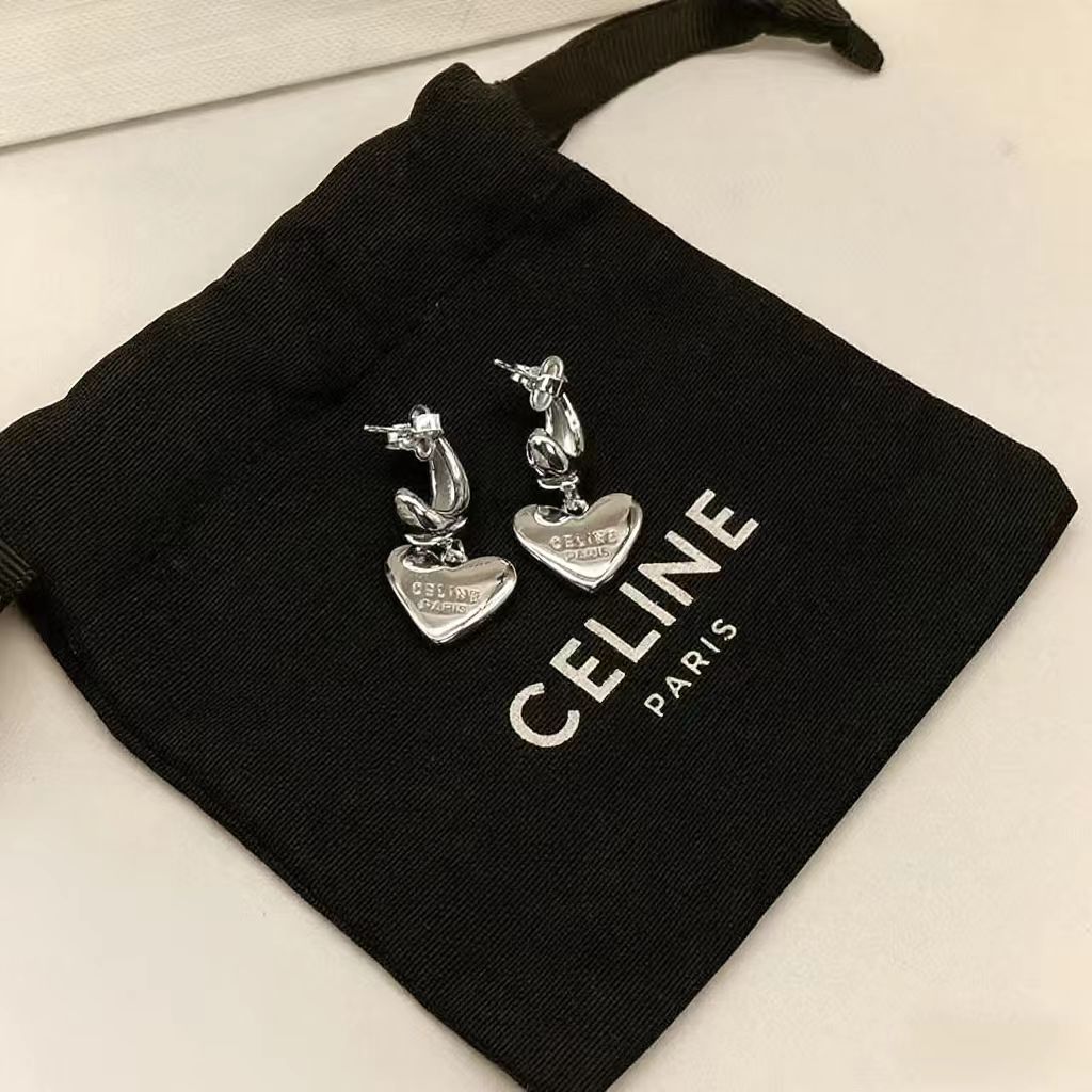 A pair of silver-tone Celine horse and heart charms resting on a black Celine Paris drawstring pouch.