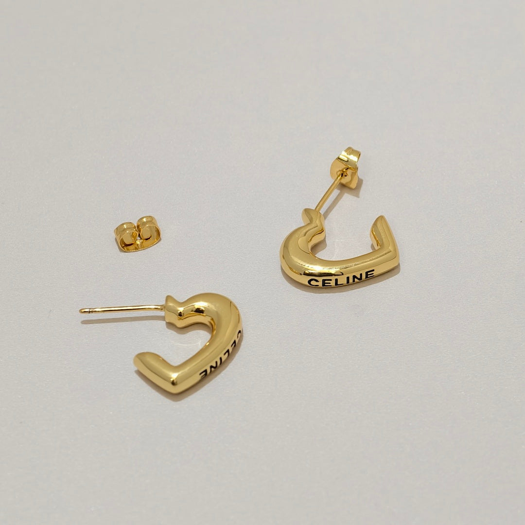 Gold-tone Celine crescent-shaped hoop earrings with the brand name engraved on the front, displayed on a light gray background.