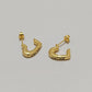 A pair of gold Celine huggie hoop earrings with the brand name engraved on the front, displayed on a neutral light gray background.