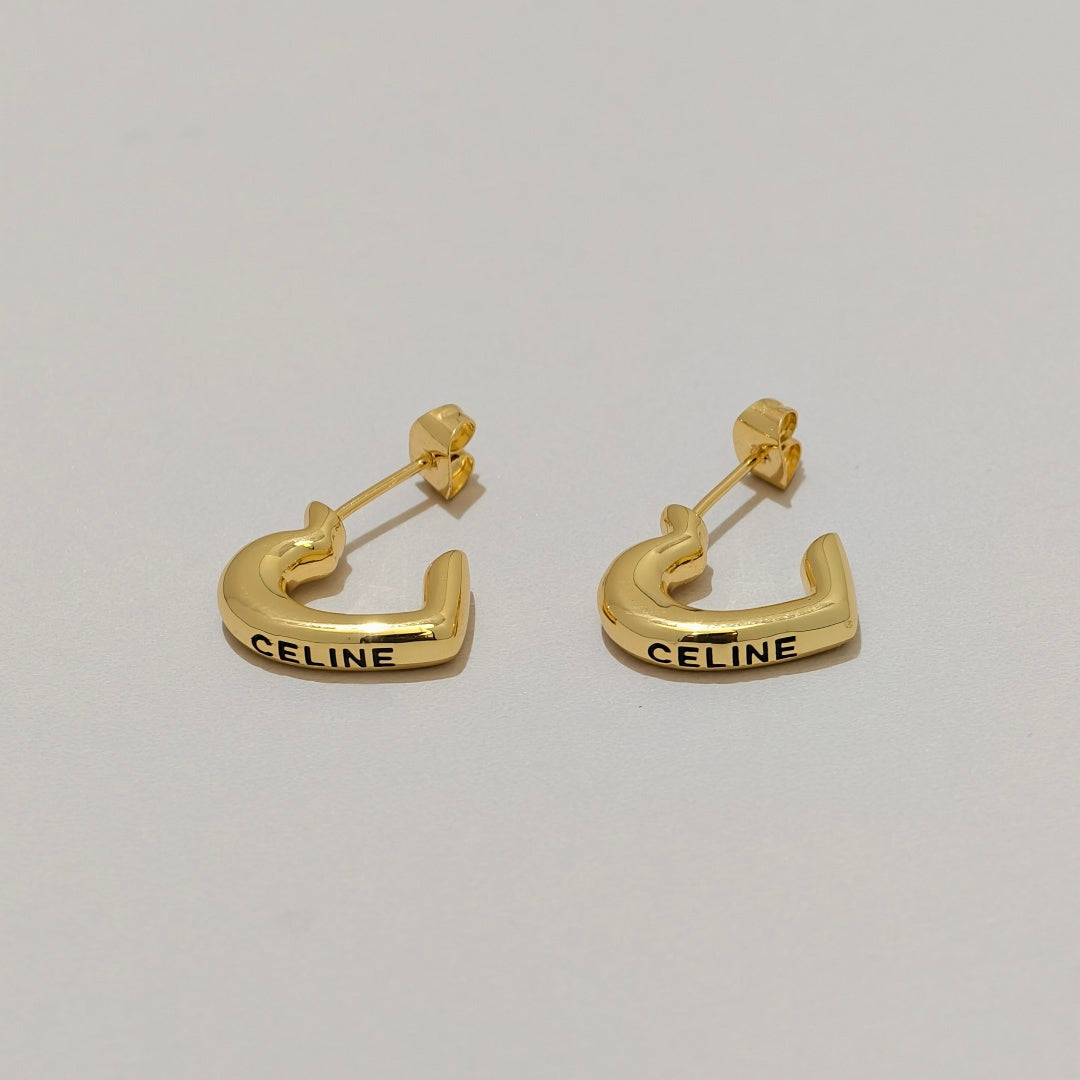 A pair of gold Celine C-shaped hoop earrings with the brand name 'CELINE' engraved in black on the front, displayed on a light gray background.