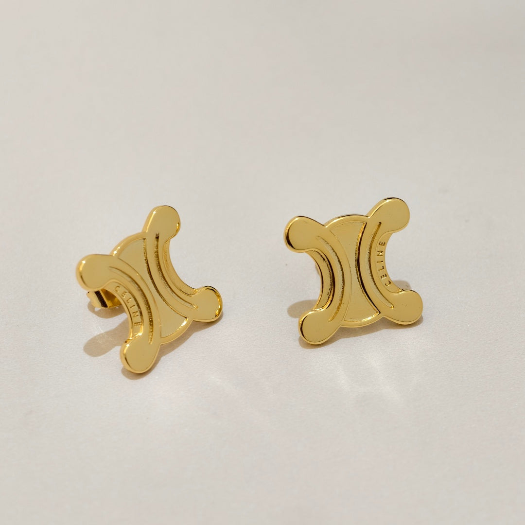 A pair of gold-tone stud earrings shaped like the Celine Triomphe symbol, shown on a clean, light off-white background.