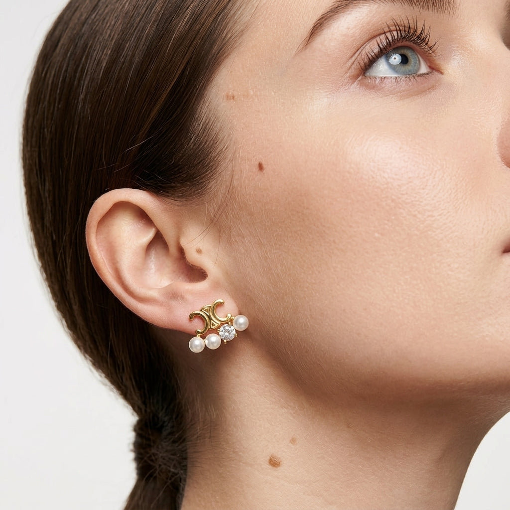 A close-up of a model's ear wearing a gold crescent moon stud earring adorned with three small white pearls.