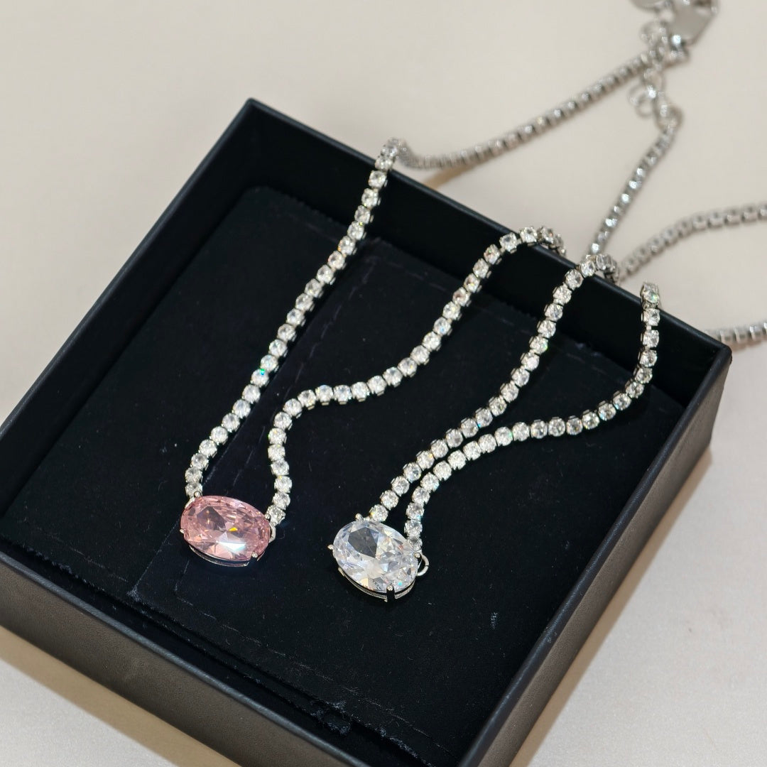 Two silver-toned beaded necklaces displayed in a black jewelry box. One necklace has an oval pink gemstone pendant, and the other has an oval clear gemstone pendant.