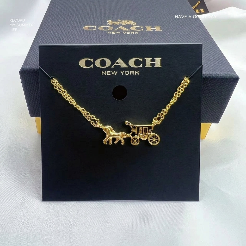 A gold-tone Coach necklace with a horse-drawn carriage pendant, displayed on a black Coach New York card and box.