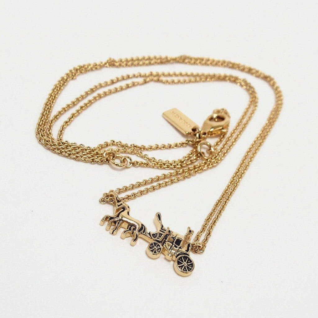 A gold-tone double-strand necklace featuring a detailed horse-drawn carriage pendant with black enamel accents, displayed on a clean white background.