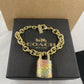 A Coach New York bracelet with a gold-tone chain and a colorful padlock charm, displayed on its black textured brand box.