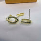 Gold hoop earrings with a polished finish, shown with their metal posts and a small branded tag on a white textured surface.