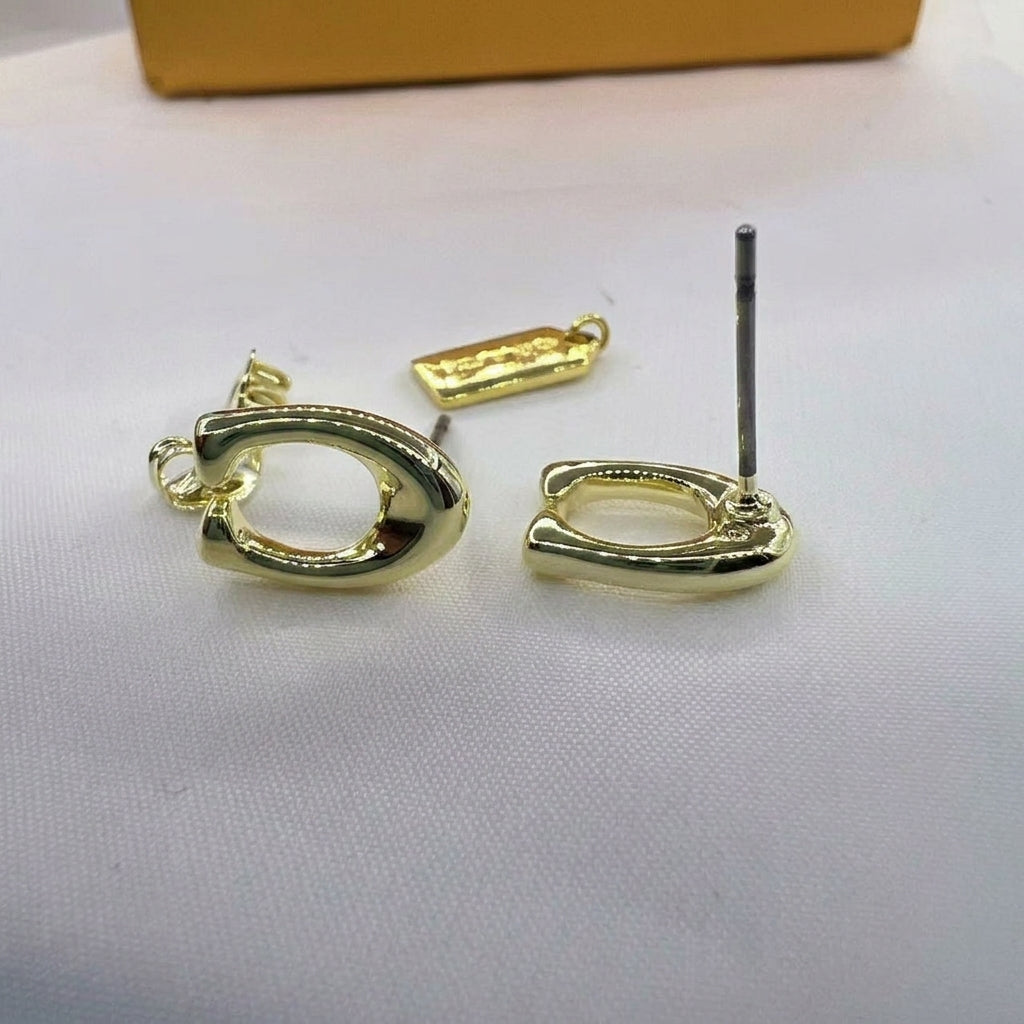 Gold hoop earrings with a polished finish, shown with their metal posts and a small branded tag on a white textured surface.